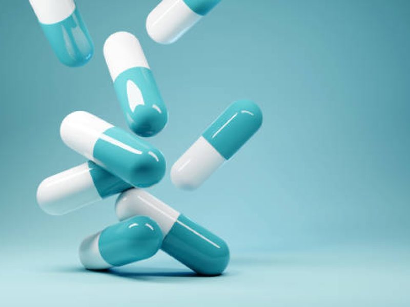A group of antibiotic pill capsules fallling. Healthcare and medical 3D illustration background.